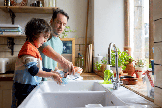 Dad and child do the dishes together